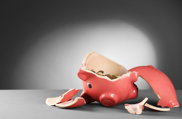 Broken pink piggy bank with coins spilling out, symbolizing financial loss and pecuniary damages.