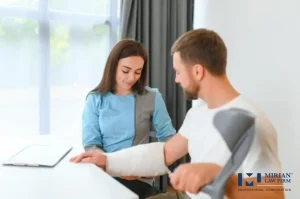 An injured man with a cast and crutches sits with a healthcare worker or legal assistant.